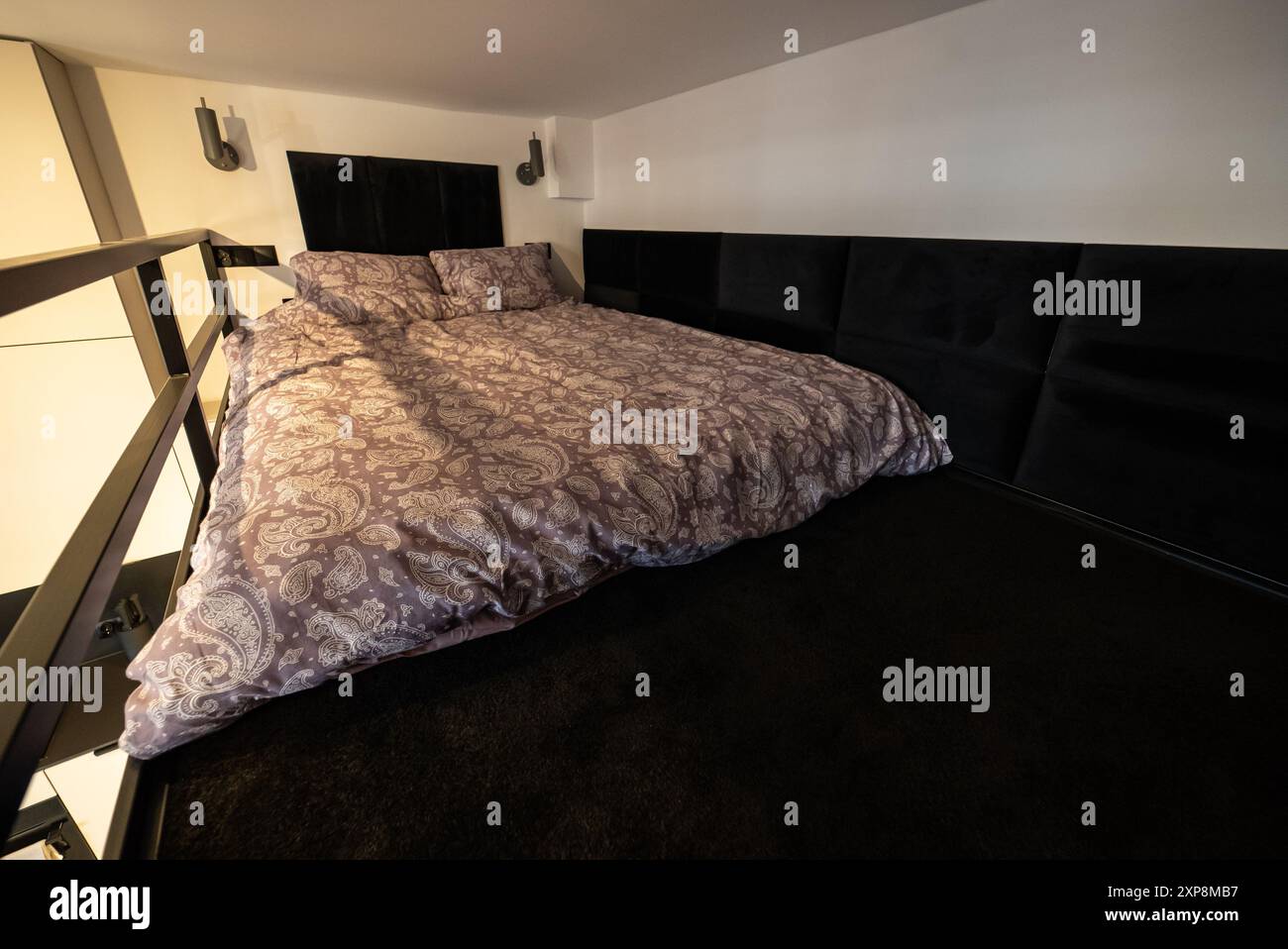 Moderno monolocale con una camera da letto sul mezzanino. Interno di una camera da letto con letto e cuscini. Appartamento piccolo e moderno con soppalco Foto Stock