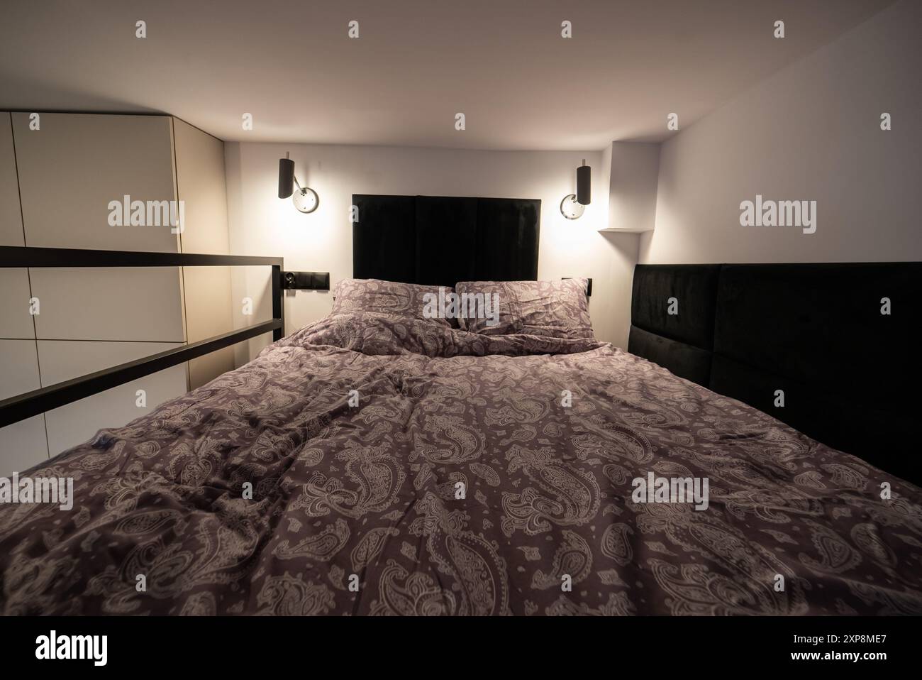 Moderno monolocale con una camera da letto sul mezzanino. Interno di una camera da letto con letto e cuscini. Appartamento piccolo e moderno con soppalco Foto Stock