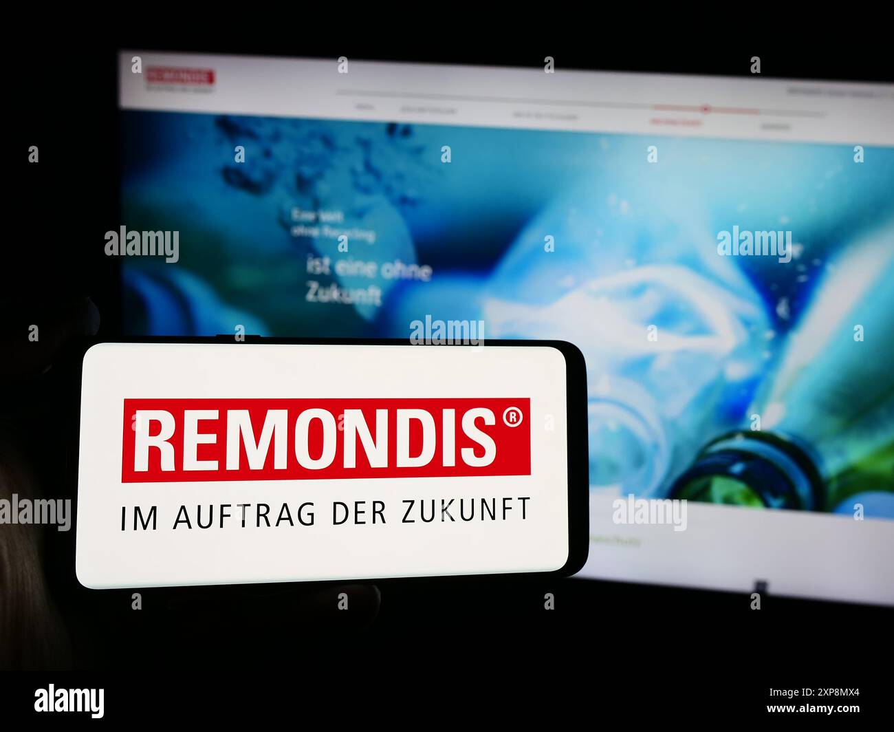 Persona che possiede uno smartphone con logo della società tedesca di gestione dei rifiuti Remondis se Co.. KG davanti al sito web. Mettere a fuoco il display del telefono. Foto Stock