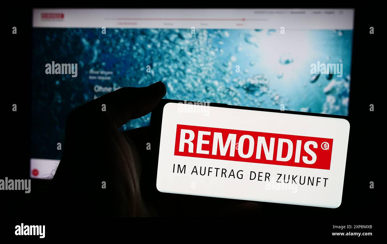 Persona che possiede un telefono cellulare con logo della società tedesca di gestione dei rifiuti Remondis se Co.. KG davanti alla pagina Web aziendale. Mettere a fuoco il display del telefono. Foto Stock