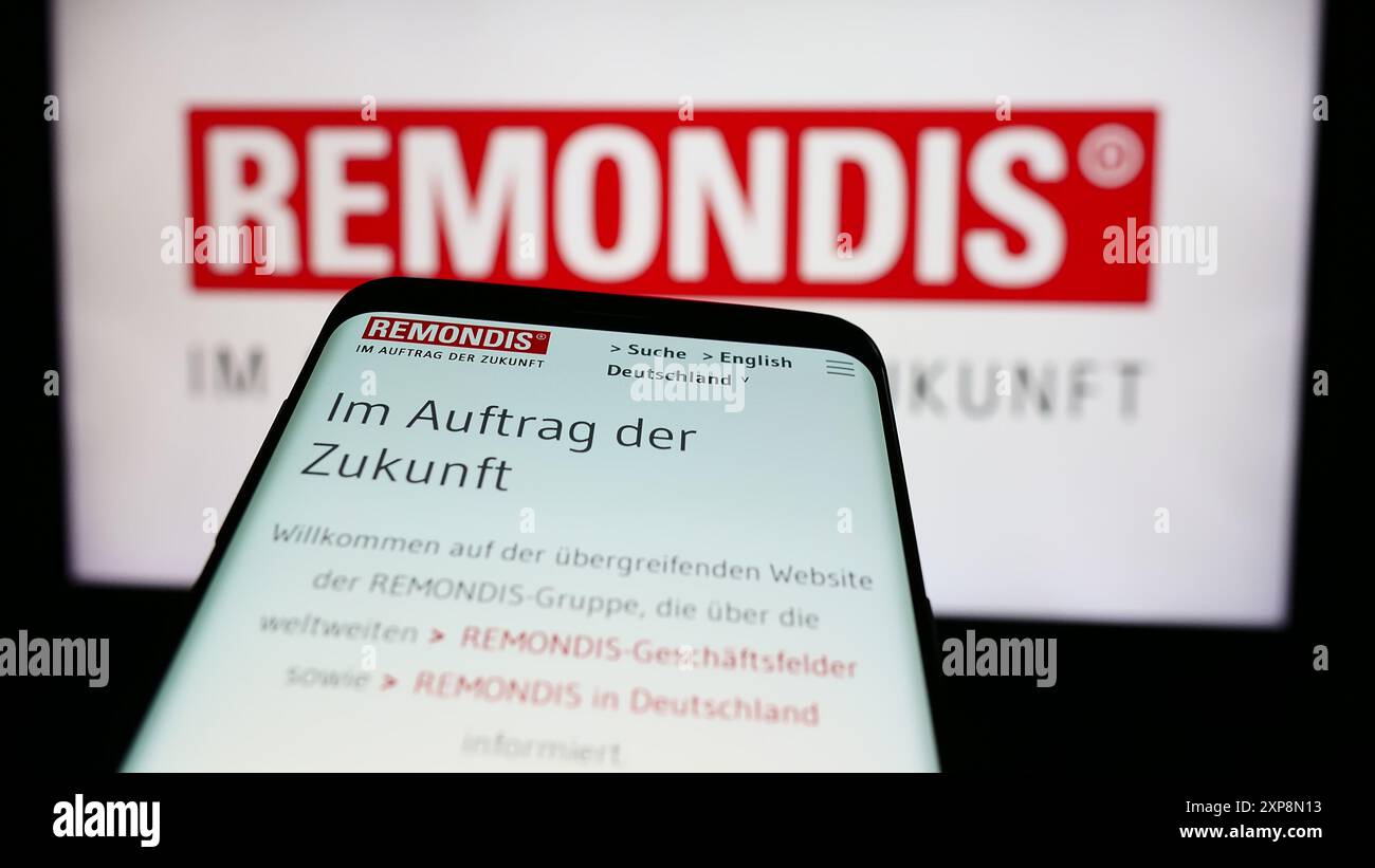 Telefono cellulare con sito web della società tedesca di gestione dei rifiuti Remondis se Co.. KG davanti al logo aziendale. Mettere a fuoco in alto a sinistra sul display del telefono. Foto Stock