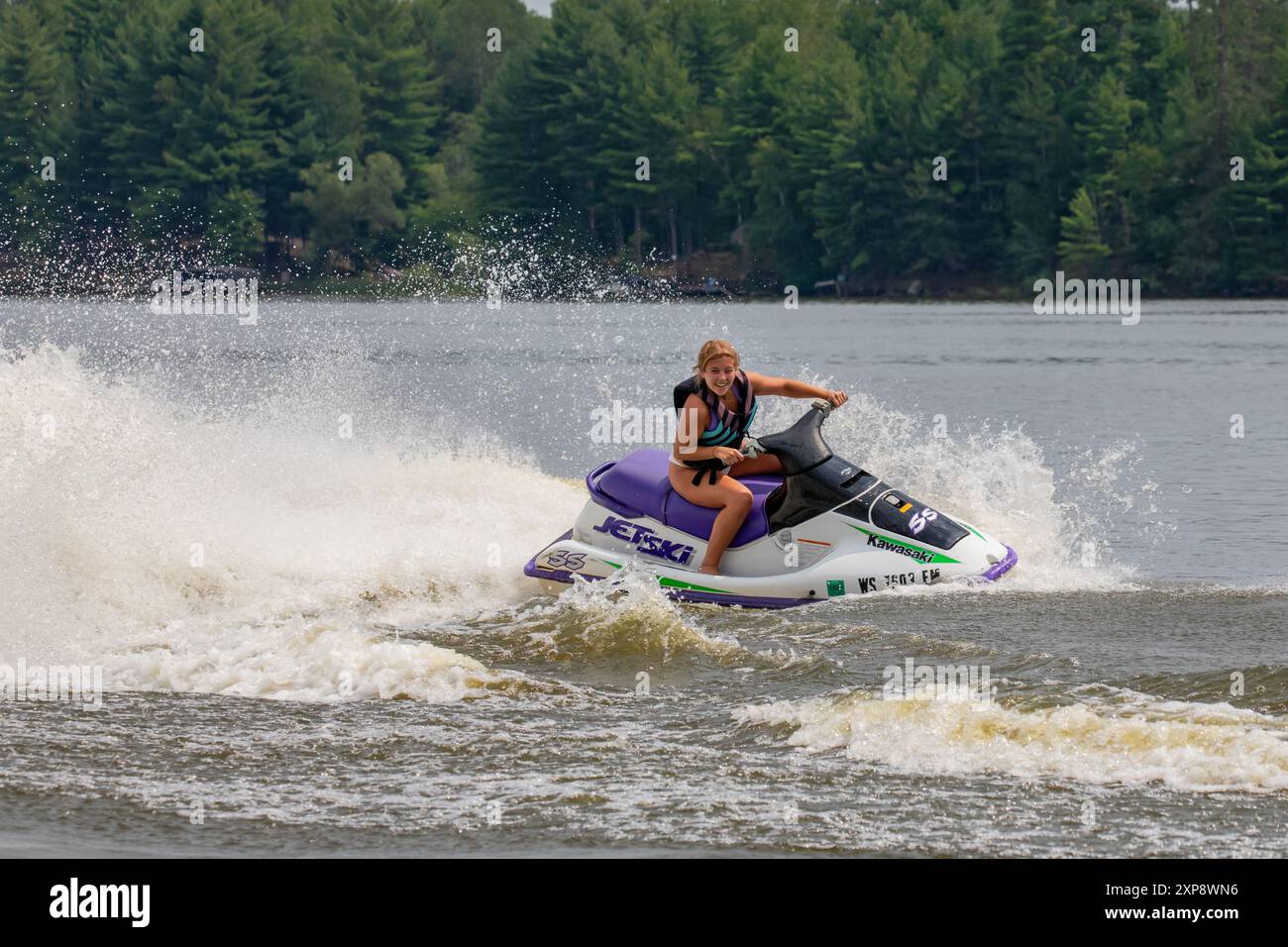 Tomahawk, Wisconsin, USA - 30 luglio 2024: Giovane donna che guida una moto d'acqua nel Wisconsin, orizzontale Foto Stock