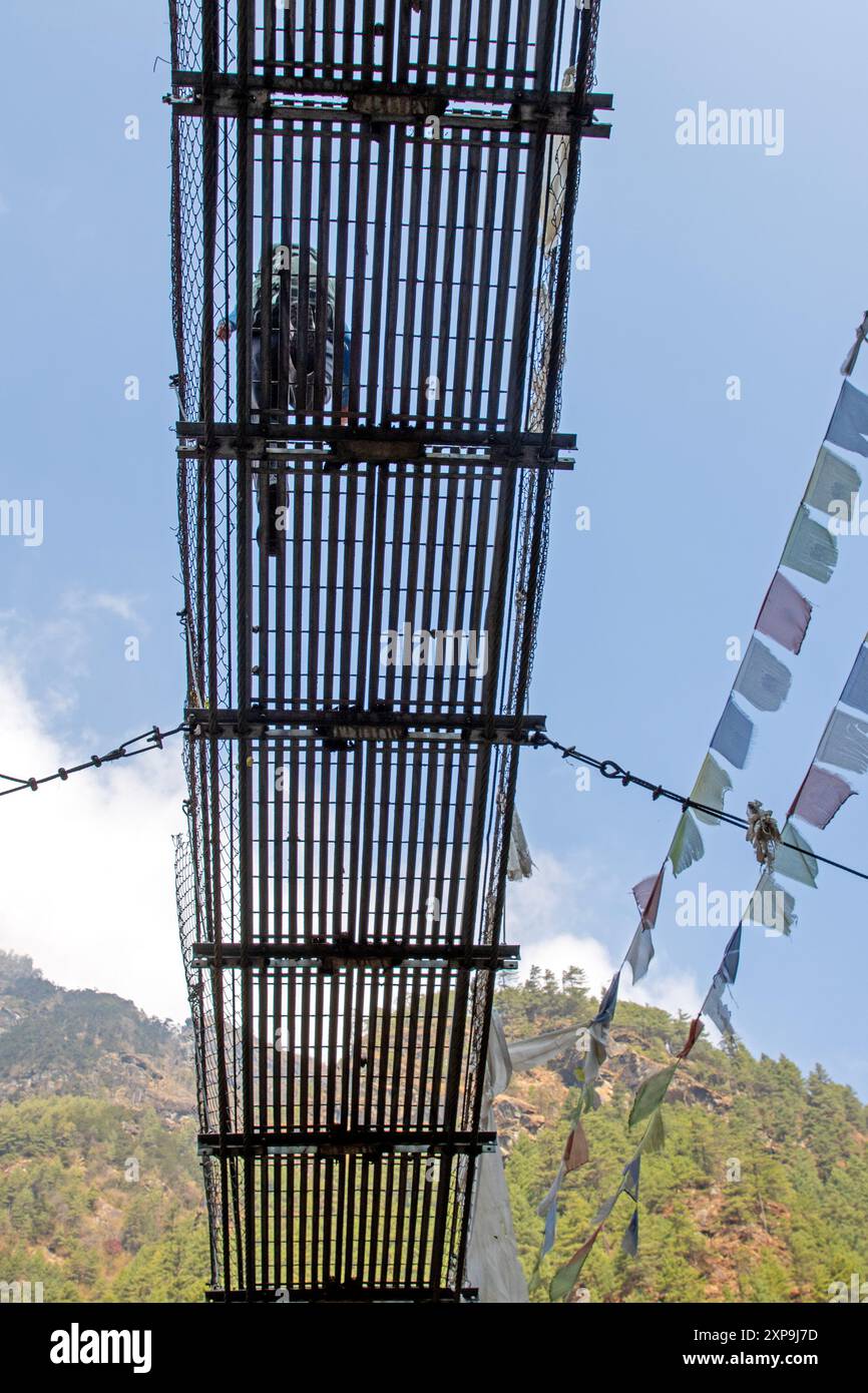 Fai trekking attraversando un ponte sospeso sul Dudh Kosi sul trekking del campo base dell'Everest Foto Stock