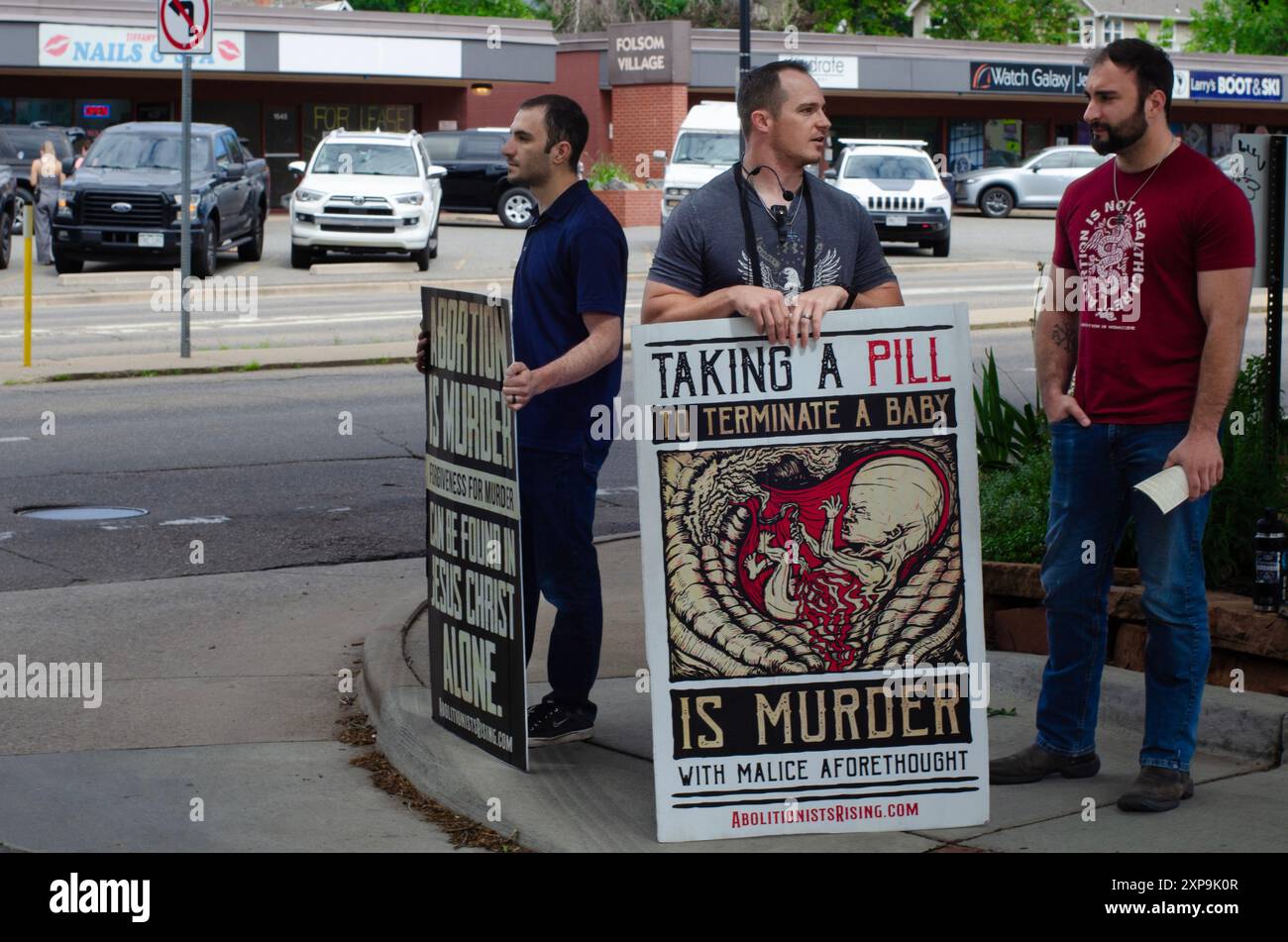 Tre uomini con cartelli che riportano messaggi anti l'aborto si trovano su un marciapiede in Folsom Street a Boulder, Colorado. Foto Stock