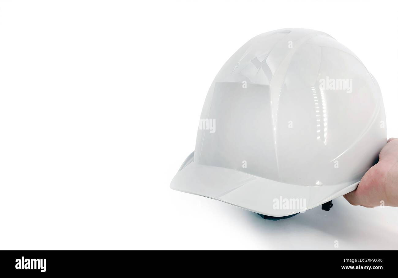 Una mano che regge un casco, cappello di protezione personale della testa di alta qualità, concetto di sicurezza prima di tutto, pronto a lavorare in cantiere, industria edile, costruzione Foto Stock