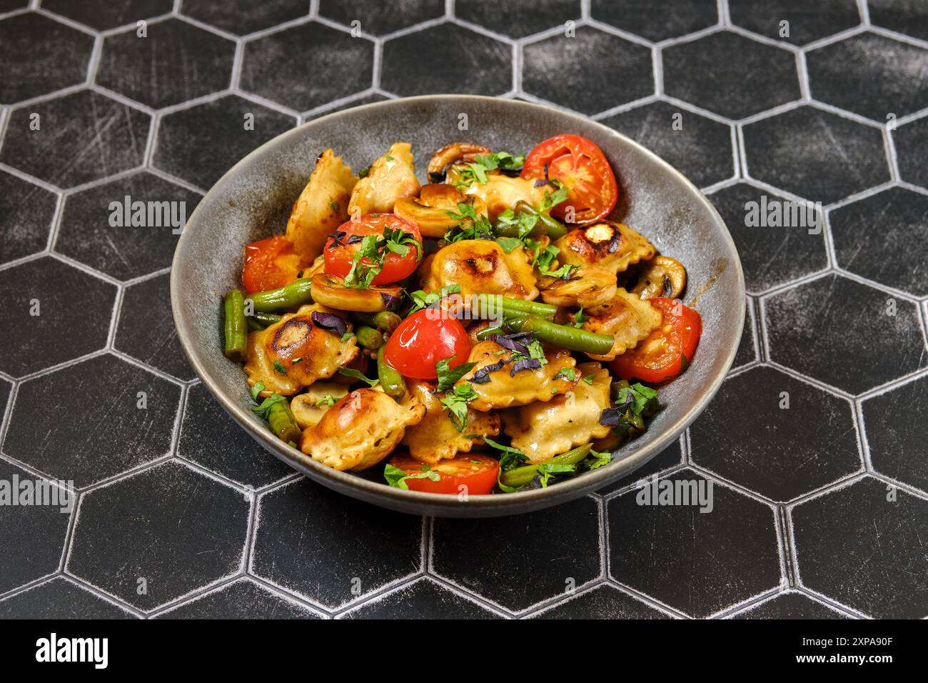 Ravioli fritti con fagioli verdi, pomodoro e funghi champignon in un piatto Foto Stock