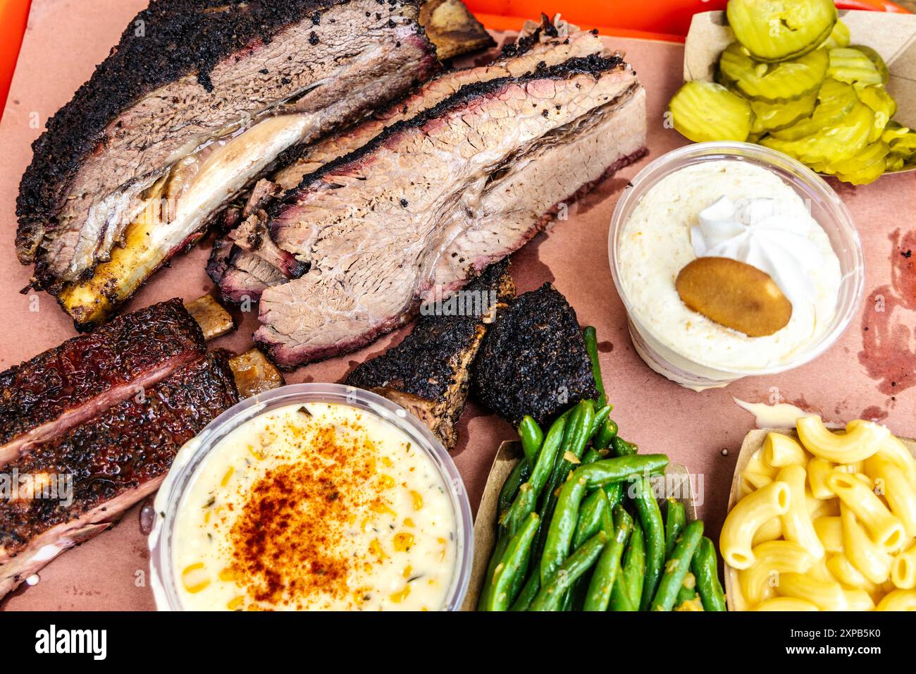 Barbecue texano - petto, costolette di maiale e manzo, crema di mais, mac e formaggio, sottaceti, budino di fagioli e banana, Terry Black's BBQ, Austin, Texas Foto Stock