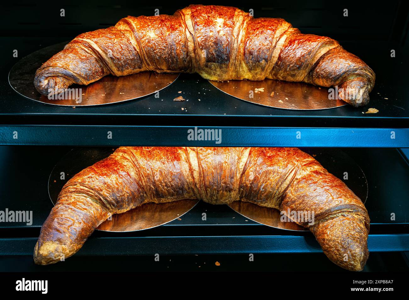 Croissant croccante appena sfornato su sfondo nero nella finestra della panetteria Foto Stock