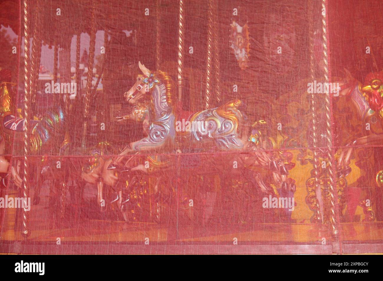 Un giro in giostra alla Fun Fair dietro una copertina rossa. Foto Stock