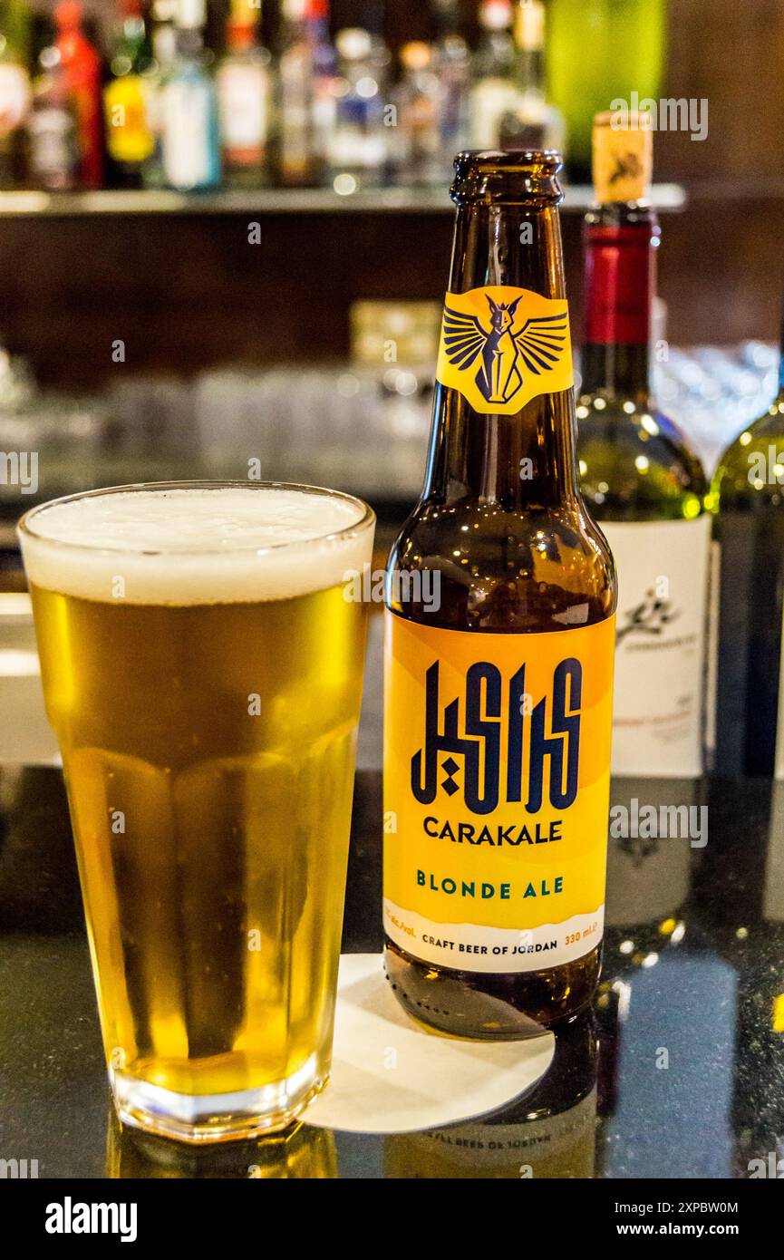 Una bottiglia e un bicchiere di birra artigianale giordana Carakale al bar, Holiday Inn Beach Hotel, Swemeh, Mar morto, Giordania, con bottiglie di vino giordano Foto Stock