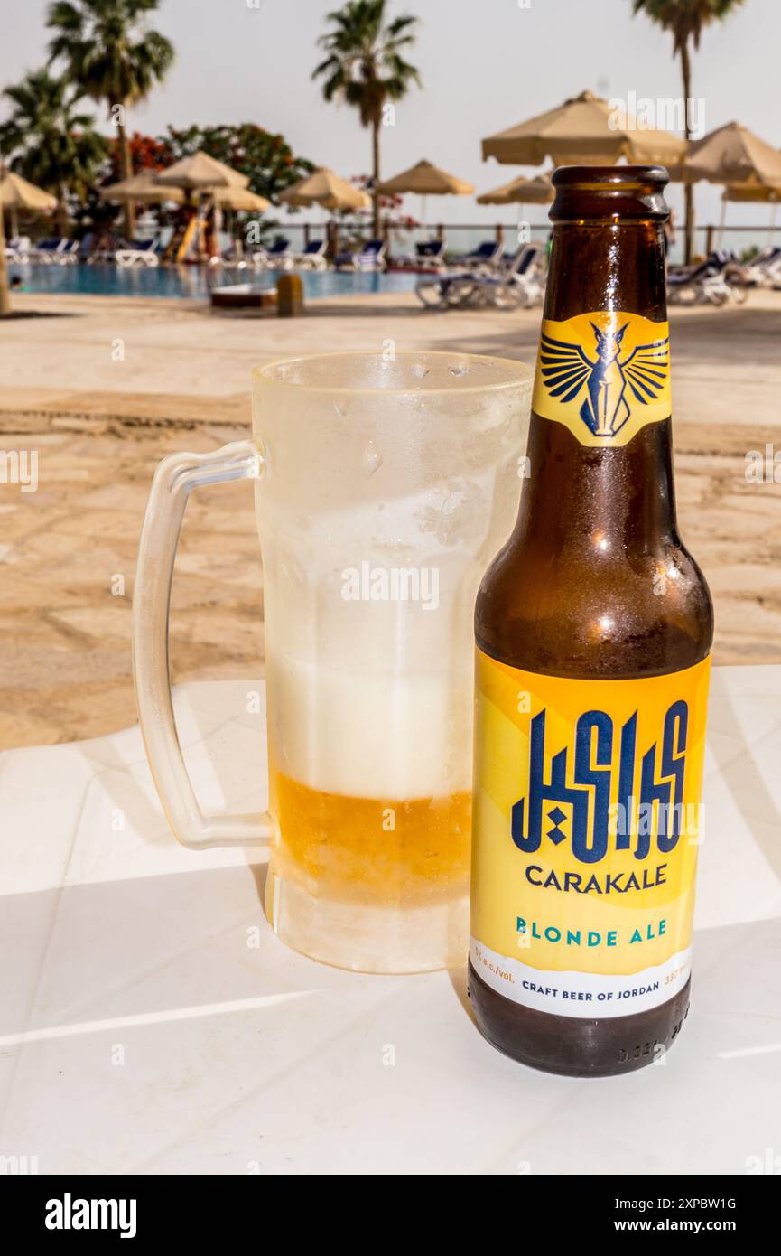 Una bottiglia e un bicchiere smerigliato di birra artigianale giordana Carakale presso la piscina dell'Holiday Inn Beach Hotel, Swemeh, Mar morto, Giordania Foto Stock