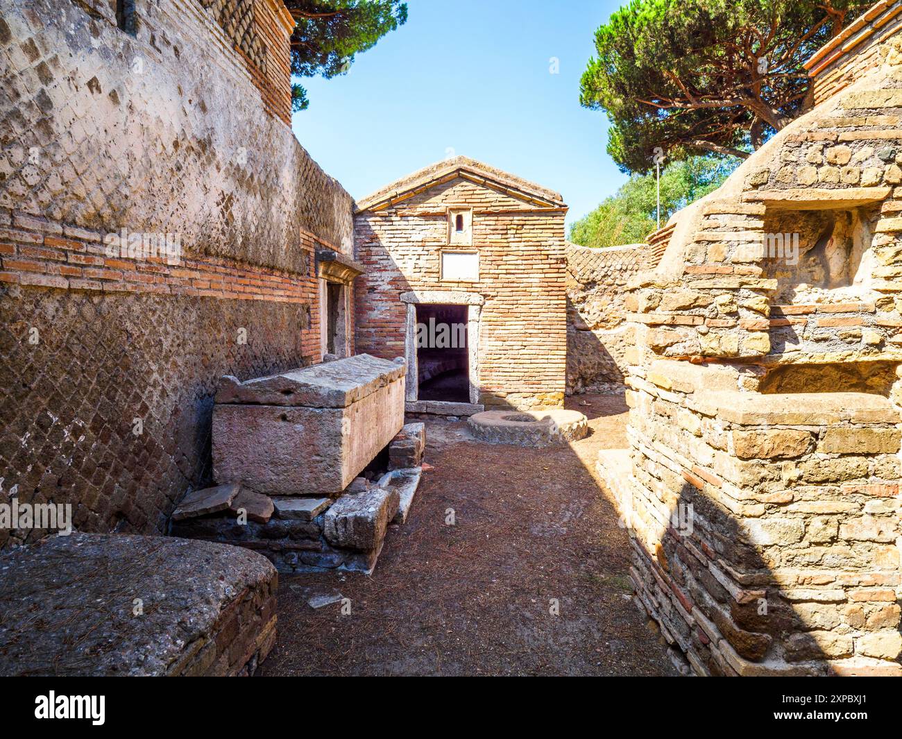 Edificio sepolcrale di una o due piani, spesso circondato da un recinto; soffitti a botte o tetti piatti; facciate in mattoni adornate con timpani triangolari, plinti, lesbiche, colonne e capitelli; piccole finestre e porte incorniciate da soglie in travertino, stipiti ed epistoli. La necropoli si sviluppò ai lati della via Flavia tra la fine del i e il IV secolo d.C. - Necropoli di Portus nell'Isola Sacra, Fiumicino, Roma, Italia Foto Stock