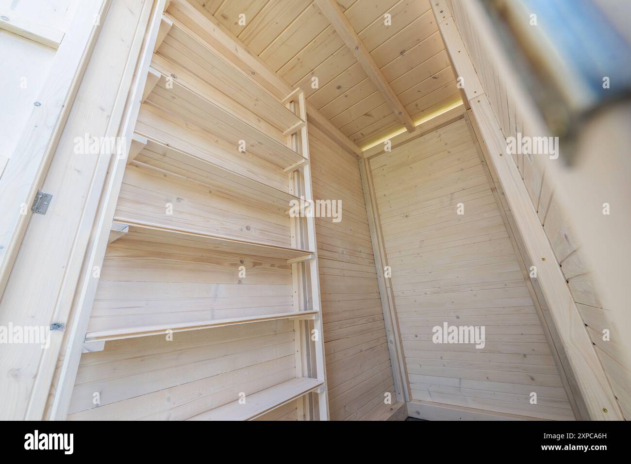 Una vista interna di un vano portaoggetti in legno caratterizzato da alti scaffali vuoti in legno di colore chiaro. Foto Stock