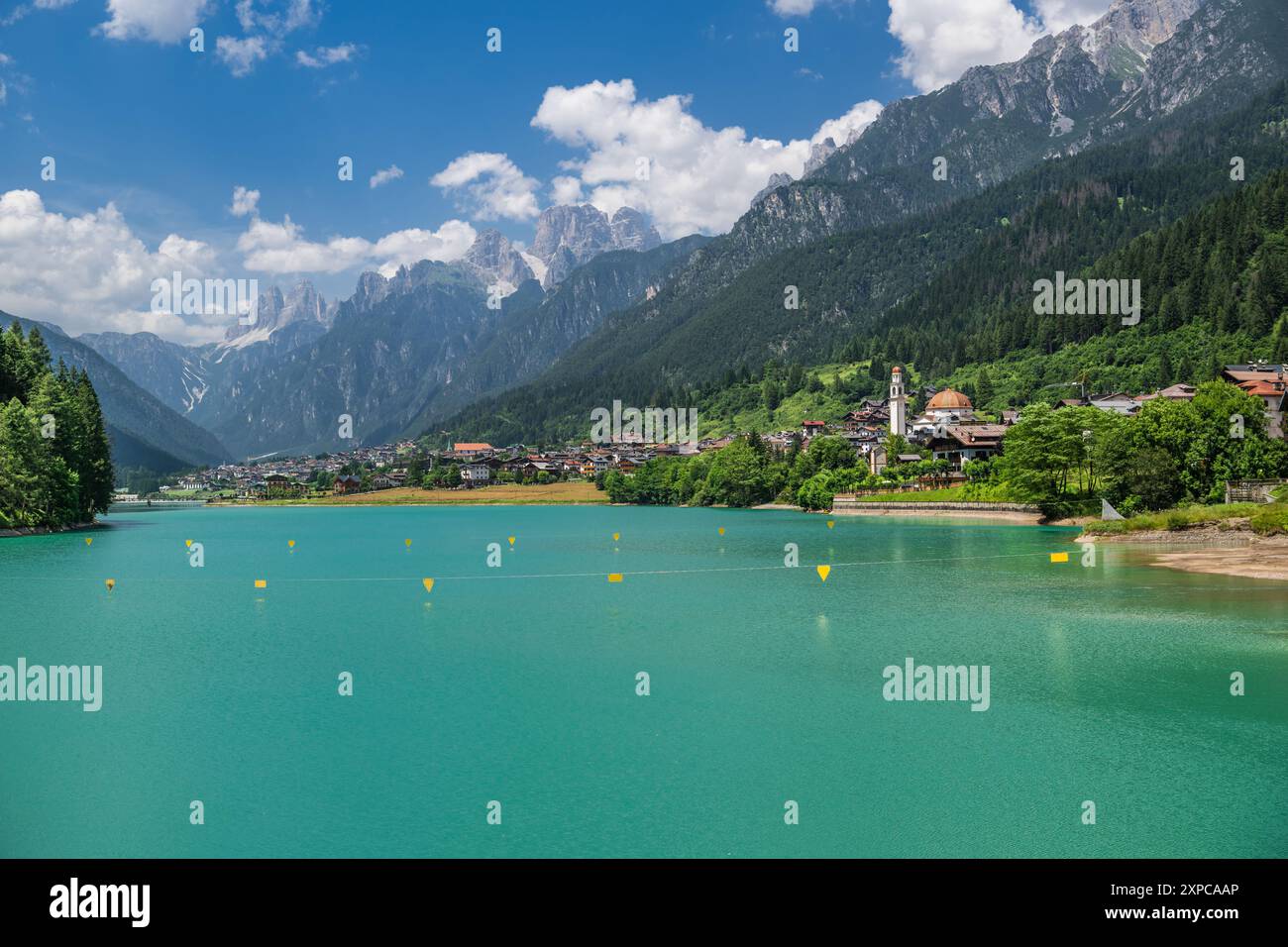 Un tranquillo lago di montagna riflette la vibrante vegetazione e la città di Auronzo di Cadore, Italia. Dolomiti. Foto Stock