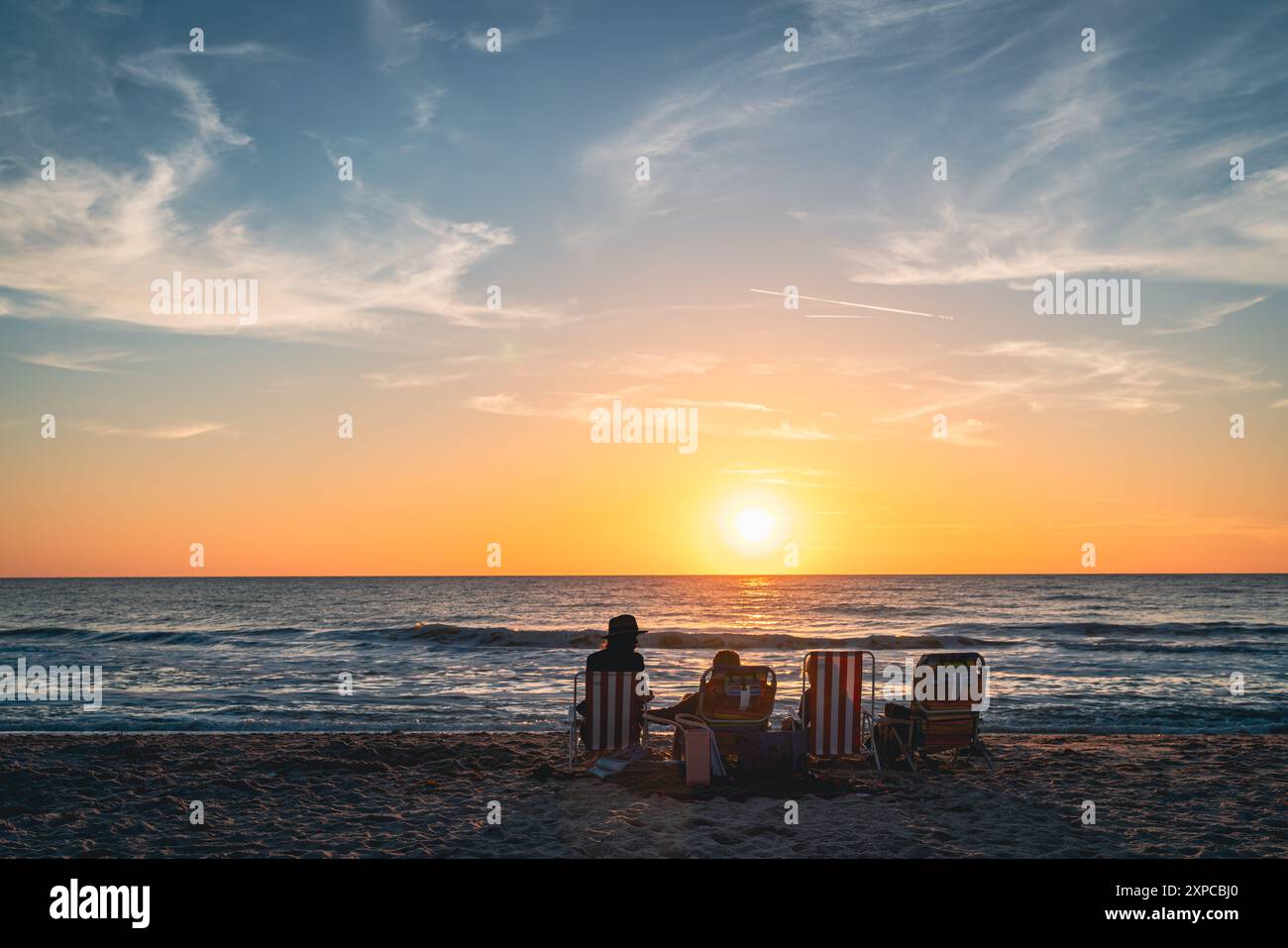 La famiglia а sta guardando il tramonto su una spiaggia di Venice, Florida Foto Stock