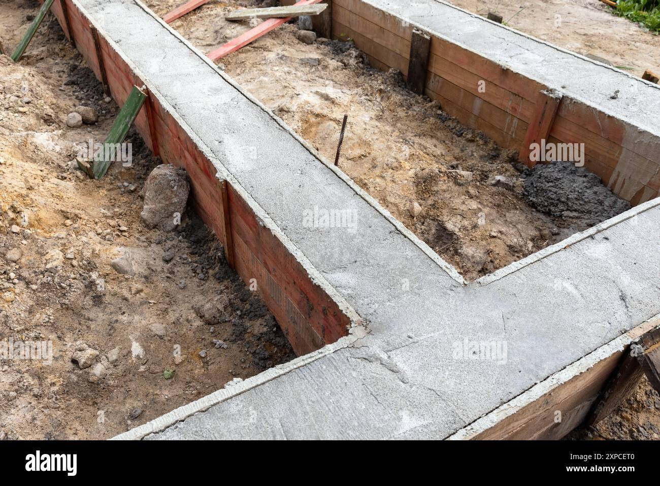 Fondamento di cemento appena posato in cassaforma di legno. La costruzione di case rurali è in corso Foto Stock