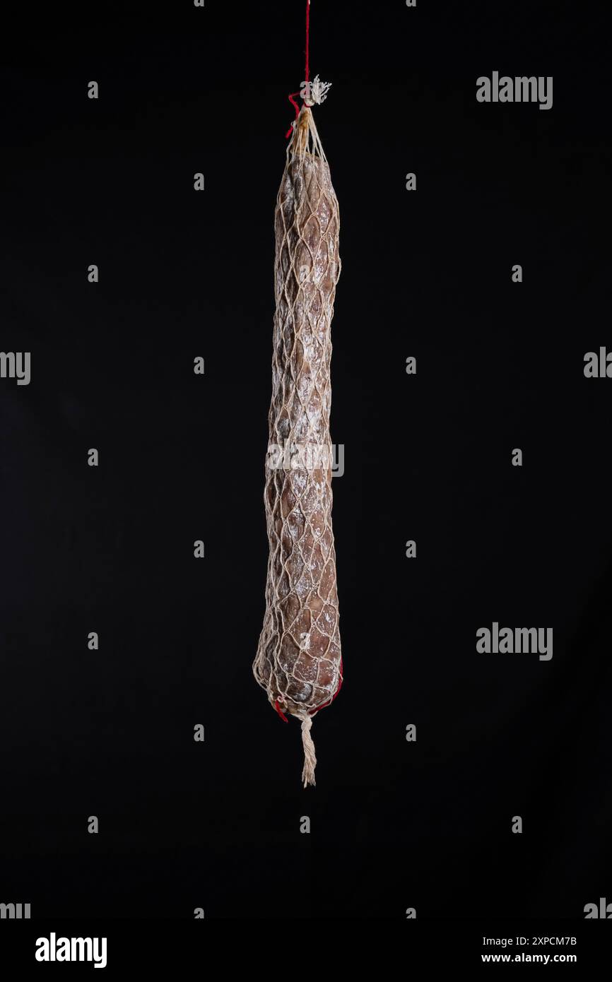 Primo piano della salsiccia Rosette de Lyon, una famosa specialità culinaria lionese su sfondo nero. Foto Stock