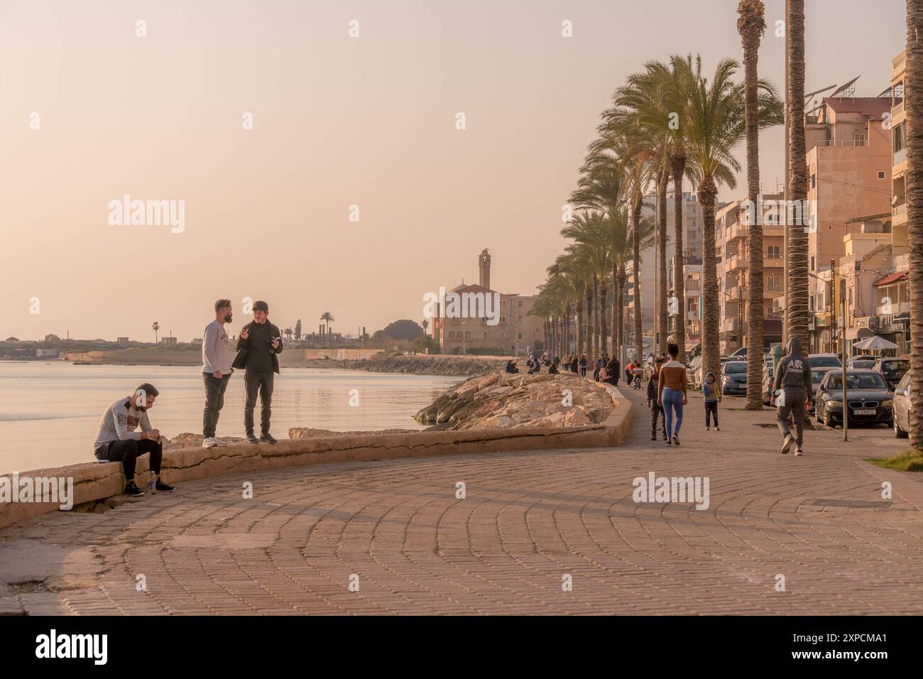 I giovani arabi sul lungomare di Tiro con le palme e la passeggiata lungo la costa del Mediterraneo, Libano, Medio Oriente. Foto Stock