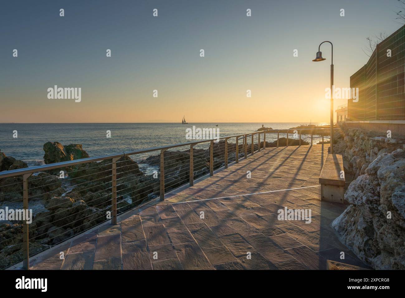 Il lungomare di Castiglioncello al tramonto e una barca in mare. Provincia di Livorno, regione Toscana, Italia Foto Stock