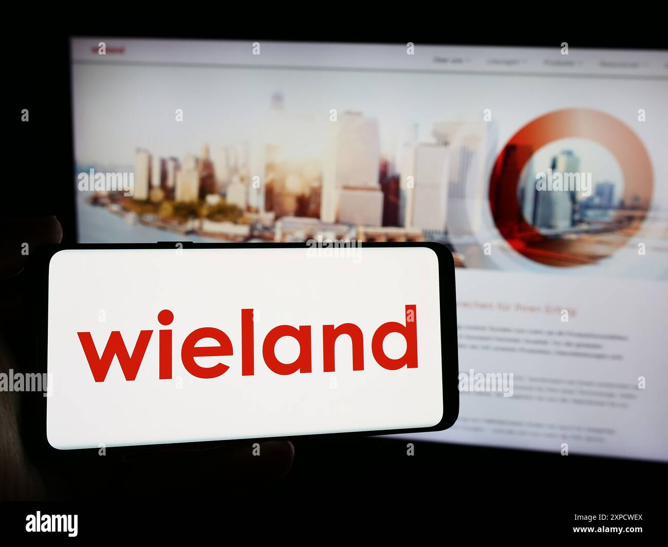 Persona che possiede uno smartphone con il logo della società tedesca di lavorazione dei metalli Wieland-Werke AG davanti al sito web. Mettere a fuoco il display del telefono. Foto Stock