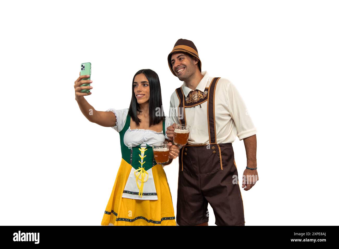 la giovane coppia bavarese, vestita con i tradizionali abiti dell'oktoberfest, si fa un selfie mentre tiene in mano le birre. L'immagine cattura il loro spirito festivo Foto Stock