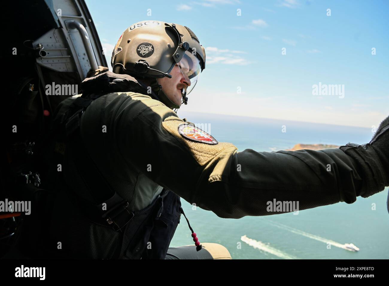 Il sottufficiale di seconda classe Carl Mayou, un tecnico di manutenzione dell'aviazione della U.S. Coast Guard Air Station San Diego, guarda da un MH-60 Jayhawk verso Petco Park a San Diego, il 4 agosto 2024. Questo volo fa parte di un apprezzamento al campo da baseball per la giornata della Guardia Costiera. (Foto della Guardia Costiera degli Stati Uniti di Nico Cavanagh, sottufficiale di terza classe) Foto Stock