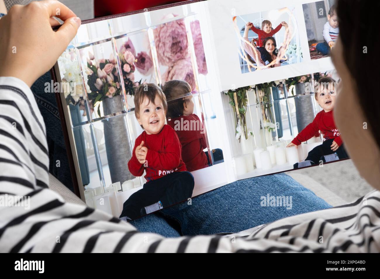 Una donna guarda un libro fotografico sul suo bambino Foto Stock