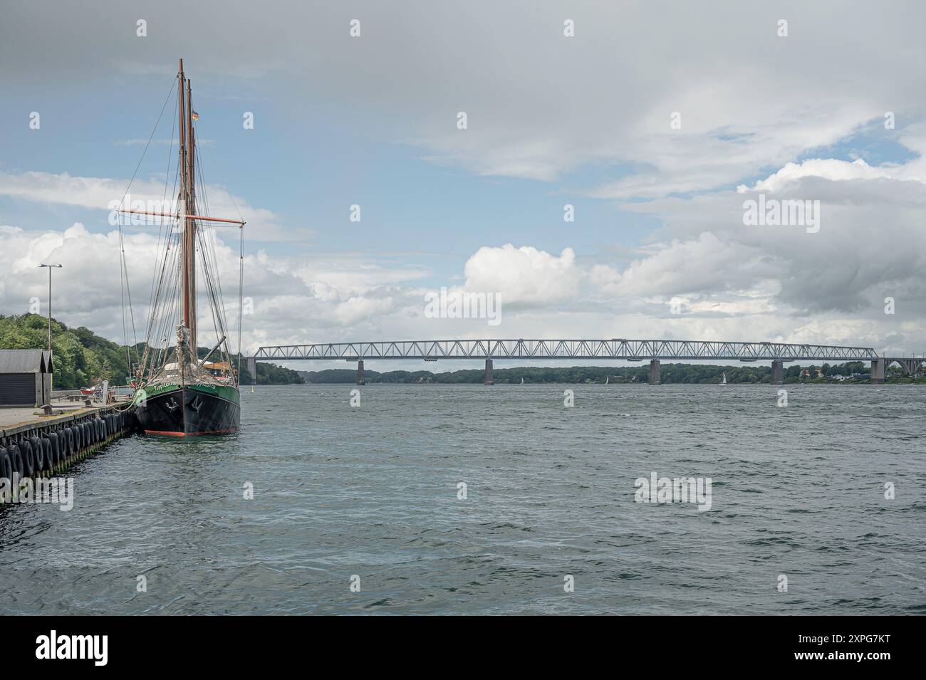 Old Little Belt Bridge e il veliero ormeggiato Pippilotta al molo, Middelfart, Danimarca, 16 giugno 2024 Foto Stock