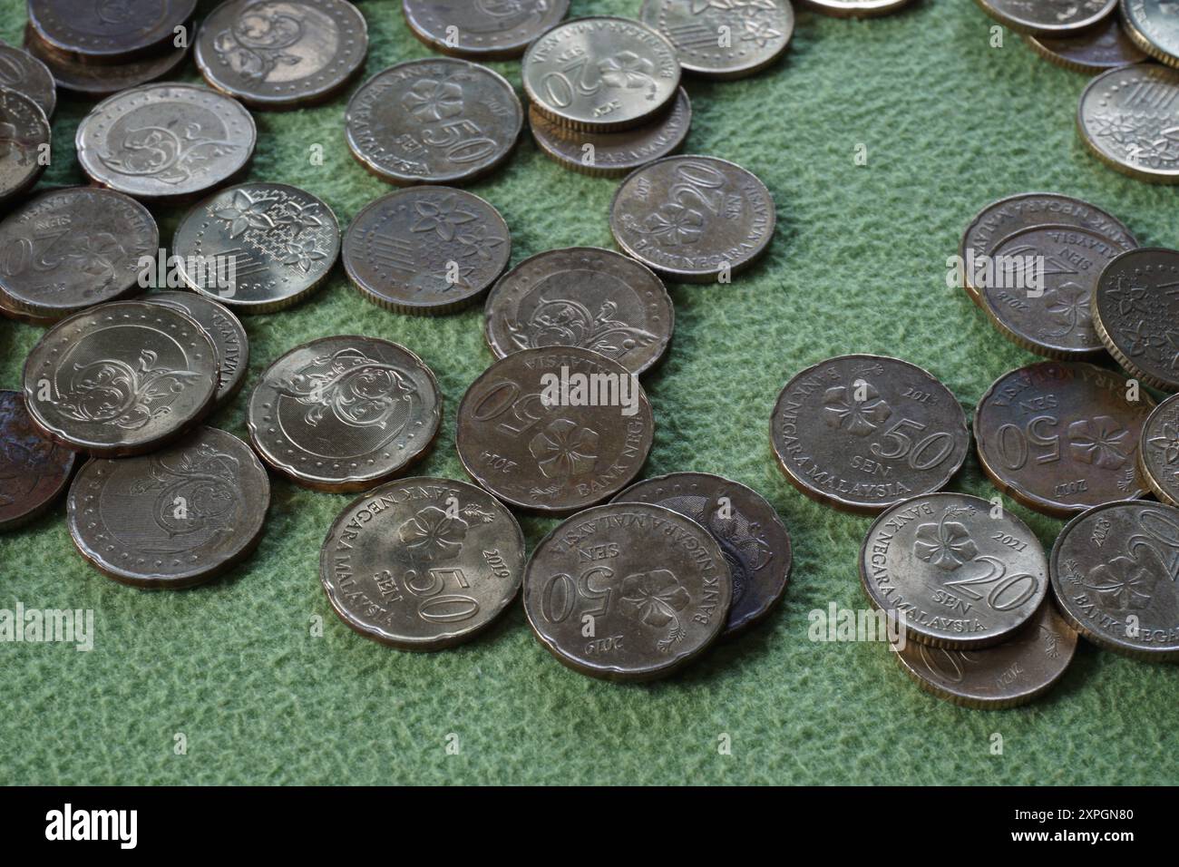 Terengganu, malesia - 23 agosto 2024: Primo piano delle monete malesi sparse su sfondo verde Foto Stock