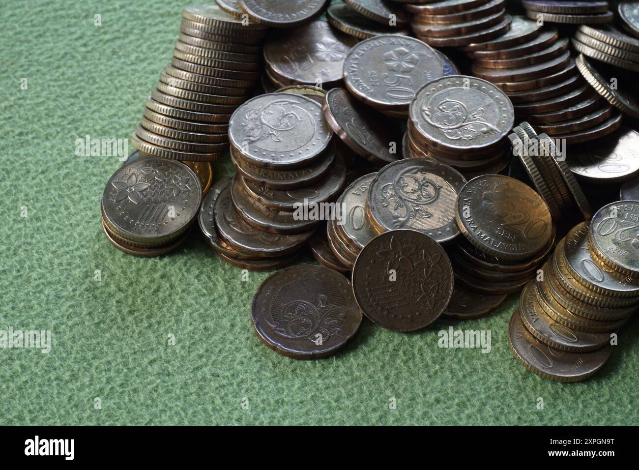 Terengganu, malesia - 23 agosto 2024: Primo piano delle monete malesi sparse su sfondo verde Foto Stock