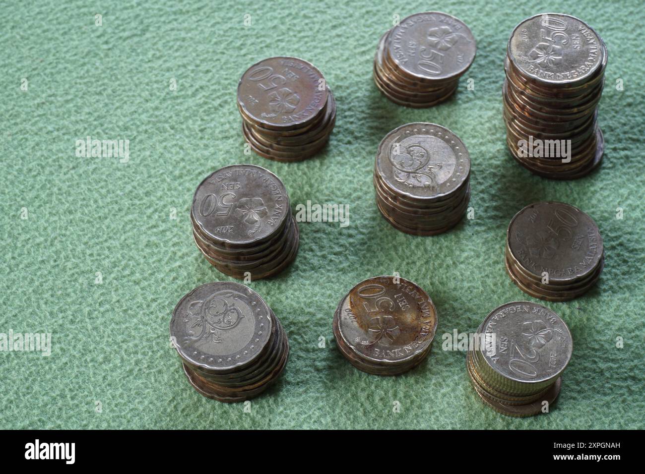 Terengganu, malesia - 23 agosto 2024: Primo piano delle monete malesi sparse su sfondo verde Foto Stock