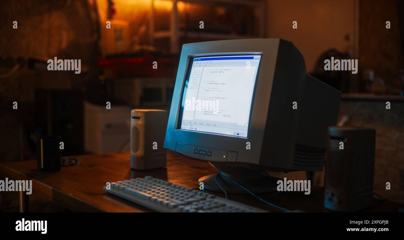 Primo piano di un vecchio computer desktop sulla scrivania dello sviluppatore di software in retro Garage. Il terminale del sistema operativo del PC datato è aperto, viene visualizzato un messaggio sullo schermo, il codice funziona correttamente. Foto Stock