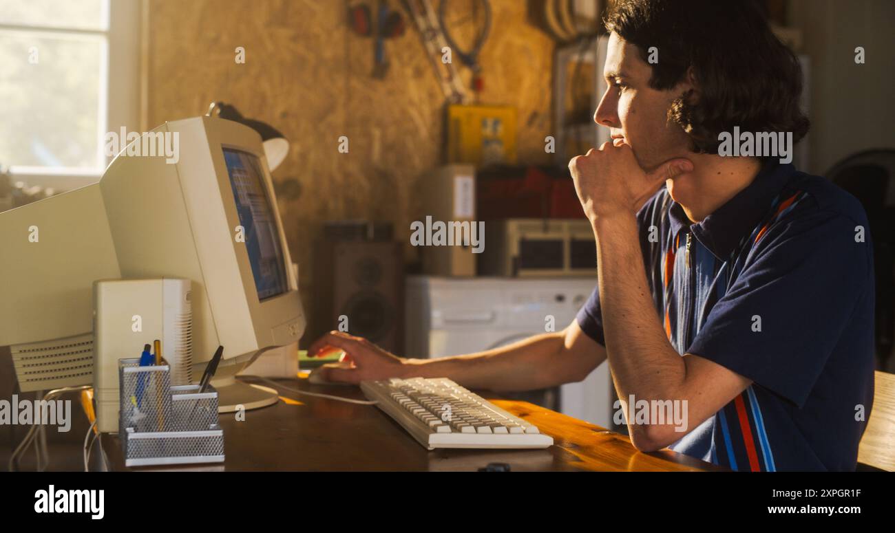 Ritratto di un ingegnere software maschio caucasico che programma su un vecchio computer desktop in retro Garage la sera. Uomo che ha avviato Tech Startup Company negli anni novanta. Codifica dell'innovativo servizio online a casa Foto Stock