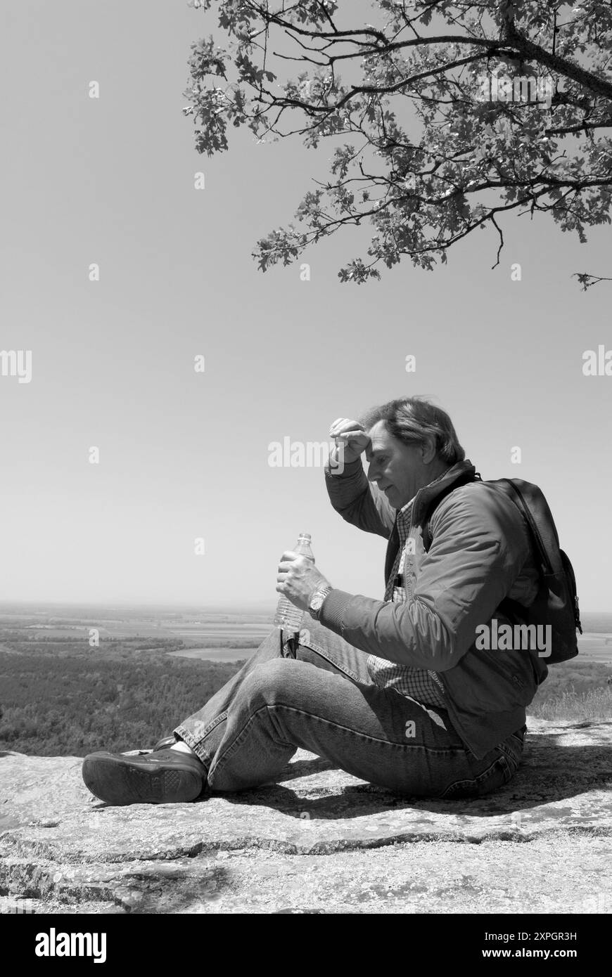 Uomo caucasico da 50 a 55 anni che riposa e beve acqua in bottiglia in un punto panoramico del Petit Jean State Park vicino a Morrilton Arkansas, USA. Foto Stock