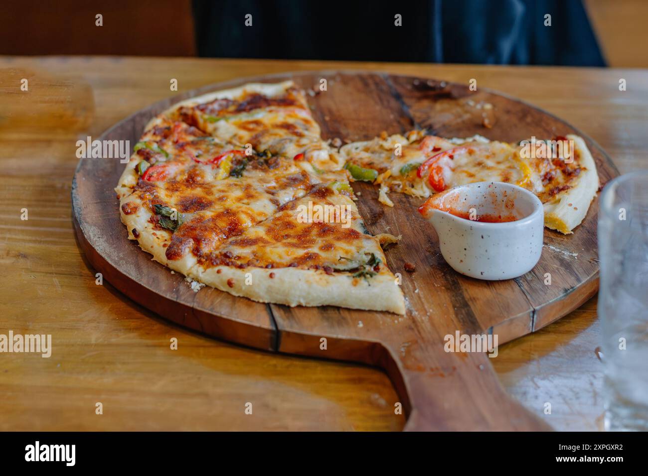 La pizza è un tipico piatto italiano servito su un vassoio di legno Composto da pane per pizza condito con verdure varie, salsicce, carne, salsa e mozzarelle Foto Stock