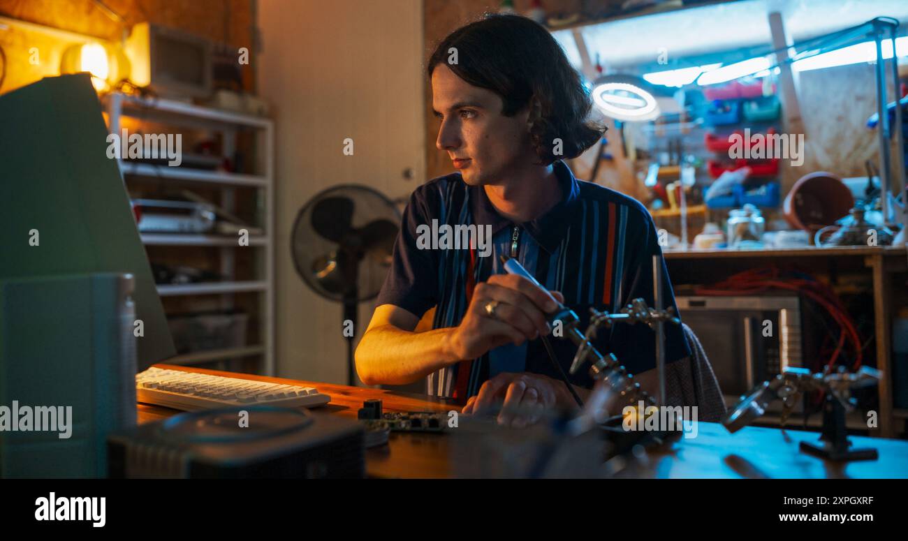 Ritratto di un ingegnere software maschio caucasico che programma su un vecchio computer desktop in retro Garage la sera. Uomo che ha avviato Tech Startup Company negli anni novanta. Codifica dell'innovativo servizio online a casa Foto Stock