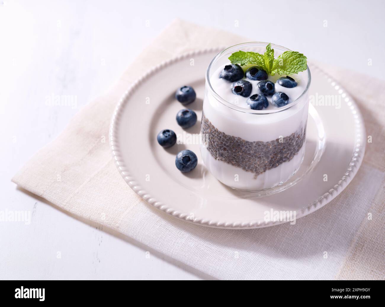 Yogurt al cocco crudo con budino di chia ricoperto di mirtilli e menta; spazio copiato; dieta vegetale Foto Stock
