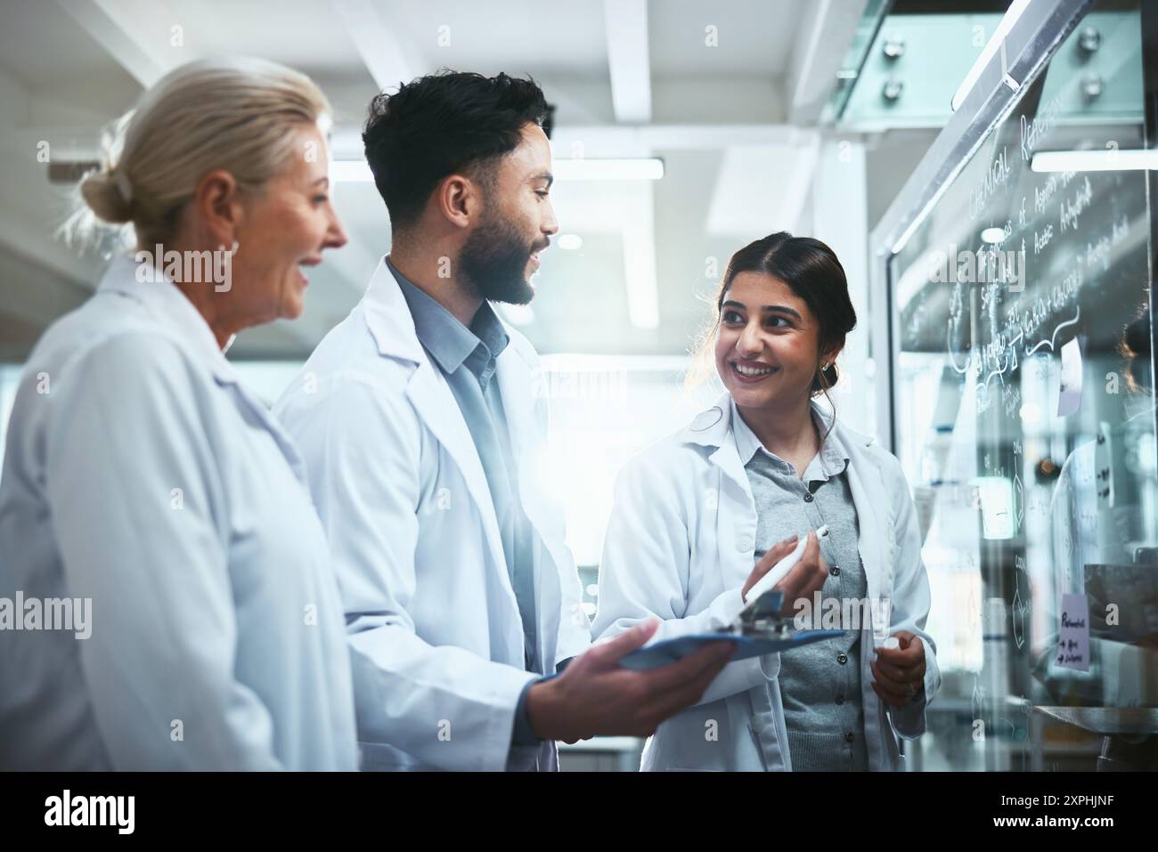 Riunione, parete di vetro e team di scienziati in laboratorio per l'innovazione farmaceutica con piano di sperimentazione farmacologica. Discussione, manager e studenti biomedici con Foto Stock