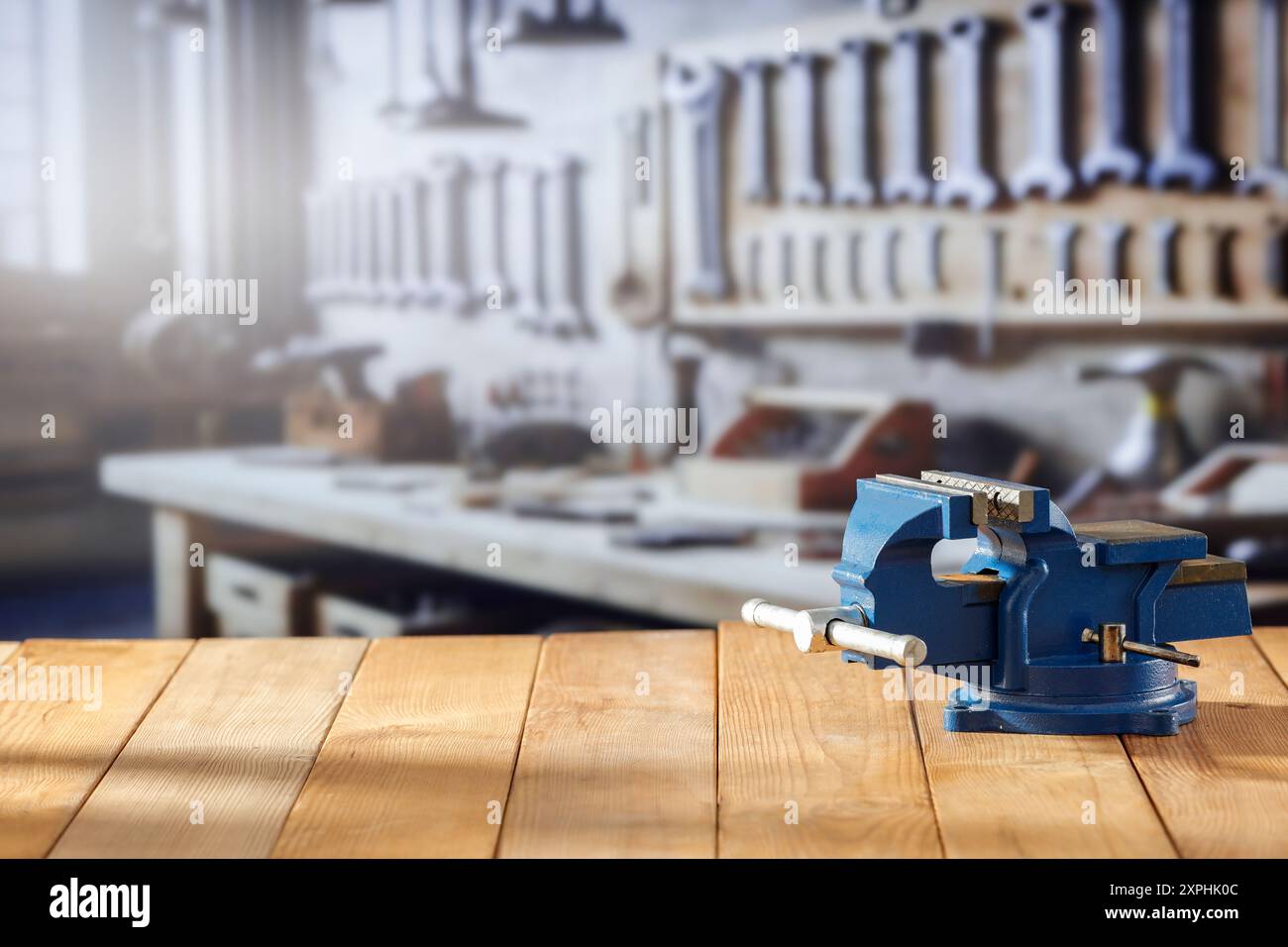 Utensili da falegname e morsa per fabbro su tavolo in legno su sfondo sfocato dell'officina, montaggio su espositore Foto Stock