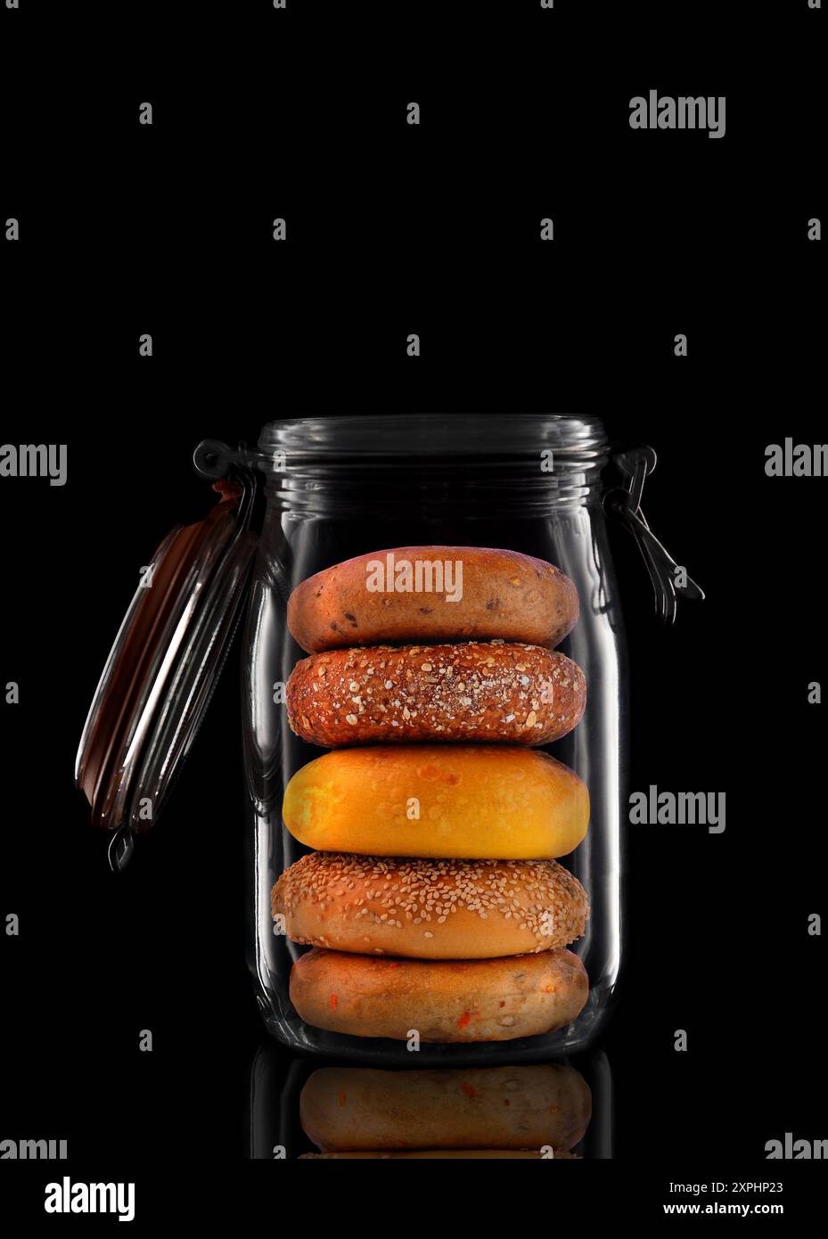 Bagel in vaschetta di conservazione in vetro o contenitore isolato sul nero con riflesso, con coperchio aperto. Foto Stock