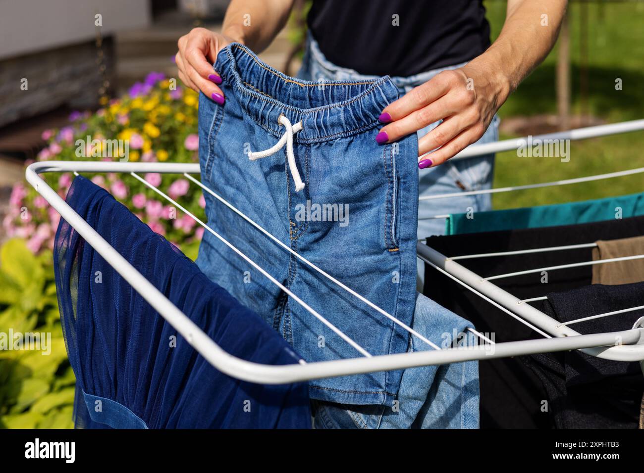 le donne passano il bucato all'aperto su un portabiti a casa nel cortile di casa. lavori domestici Foto Stock