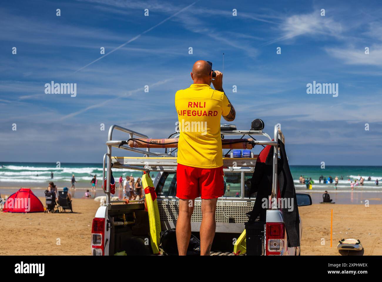 RNLI in servizio a Watergate Bay, con un attento controllo per eventuali incidenti e pronto per i salvataggi rapidi. Siate orgogliosi di questi volontari qualificati per il loro lavoro Foto Stock
