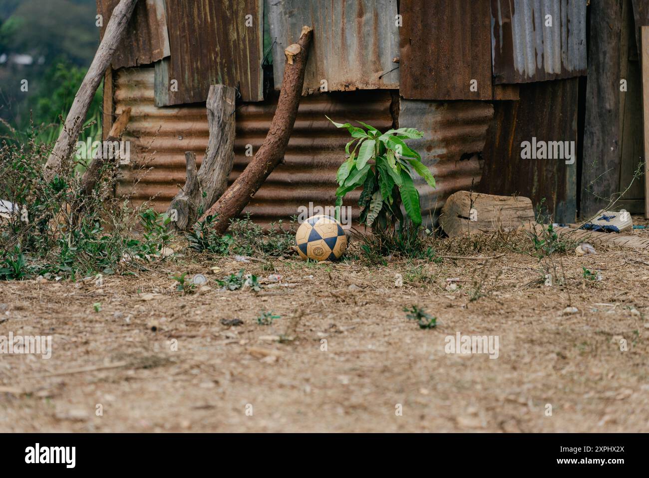 Pallone da calcio seduto accanto a una baracca di stagno in un campo Foto Stock