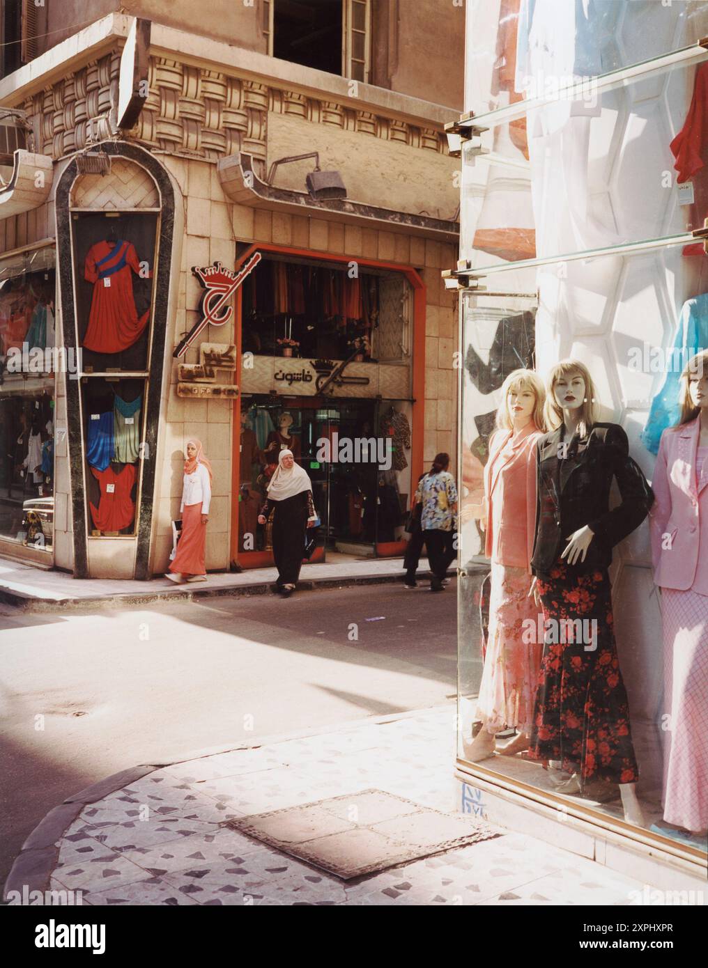 Una vivace via dello shopping ad al-Manschiya, Alessandria, Egitto, catturata nel giugno 2006. L'immagine presenta manichini nelle vetrine dei negozi e persone che passano accanto, che mostrano la vivace vita di strada e le mostre di moda. Foto Stock