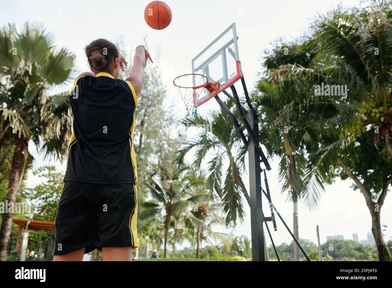 Giocare a pallacanestro sotto le palme nel campo all'aperto Foto Stock