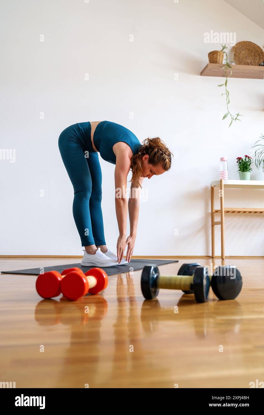 Giovane donna caucasica che indossa abbigliamento sportivo facendo esercizio fisico a casa. Stile di vita attivo e sano. Foto Stock