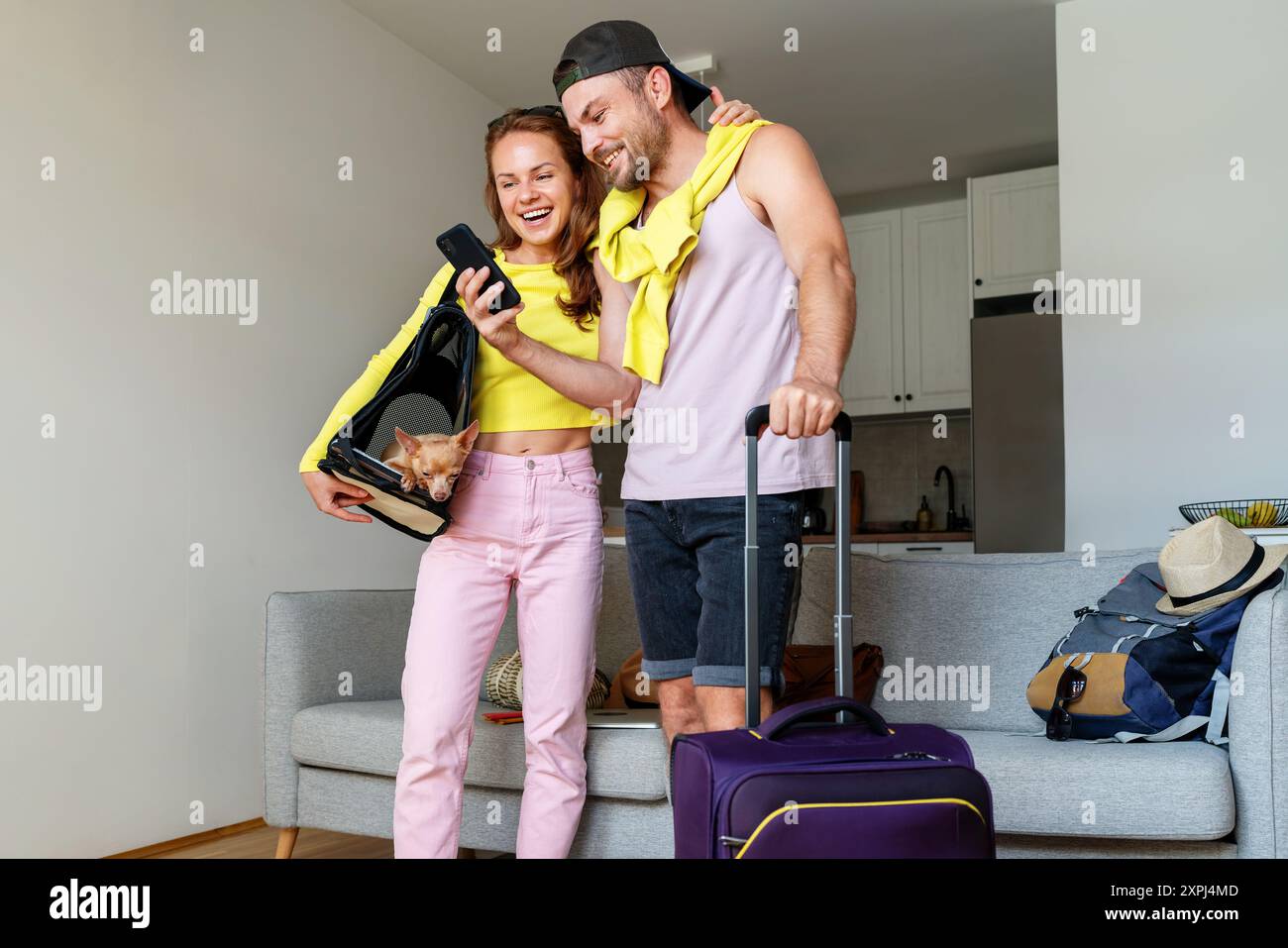Coppia con cani e borse per il sentiero guardando il telefono cellulare e sorridendo. Foto Stock