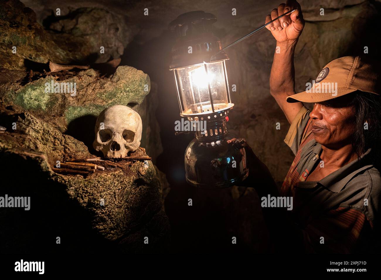 Una guida con una lanterna illumina un cranio umano in una grotta presso l'antico cimitero di Londa, il cimitero delle grotte di Toraja, Tana Toraja, Sulawesi, Indonesia Foto Stock