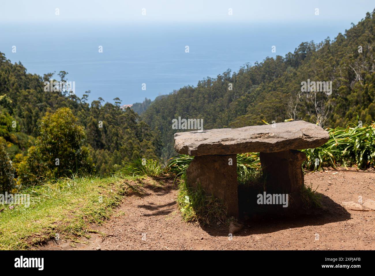 Tavolo in pietra naturale. Inflitto dalla luce del sole. Vista su una valle coperta da alberi. Acque blu dell'oceano Atlantico sullo sfondo. Leva Foto Stock