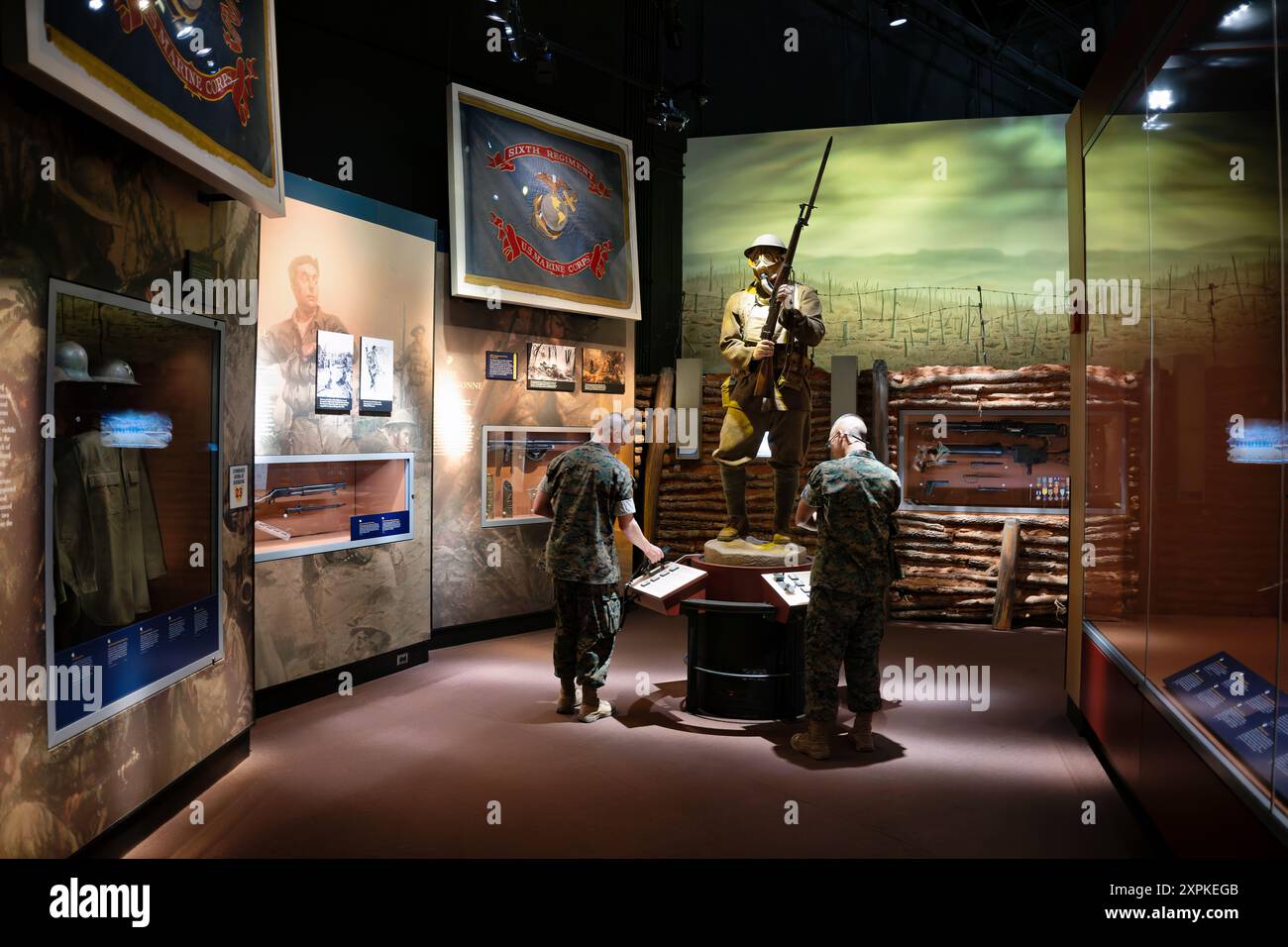 National Museum Of The Marine Corps World War I Exhibit Triangle Virginia | TRIANGLE, Virginia — Due Marines in mimetica moderna studiano un display interattivo accanto alla figura della sentinella della trincea con maschera antigas nella galleria della Prima Guerra Mondiale del National Museum of the Marine Corps, confrontando i membri del servizio di oggi con la storia della Grande Guerra del Sesto Reggimento. Il chiosco con schermo touch consente ai visitatori di esplorare artefatti legati ai combattimenti dei Marines durante la guerra delle trincee e la guerra chimica del 1918. Foto Stock